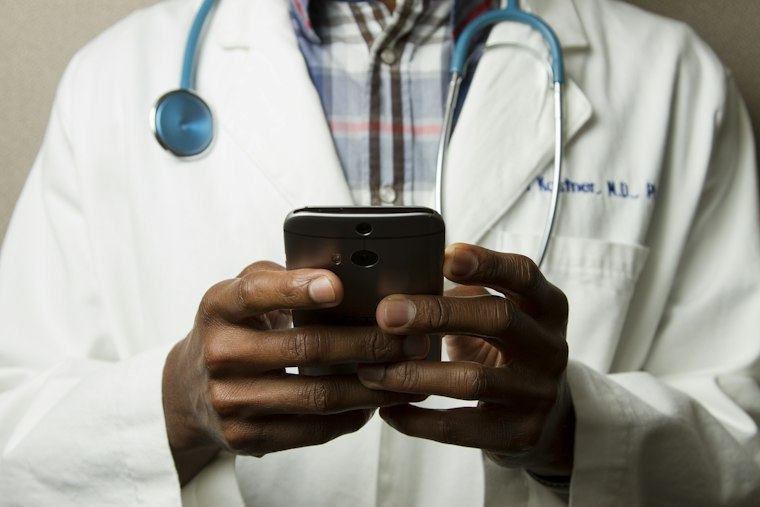 Healthcare professional with a stethoscope reviewing a mobile device